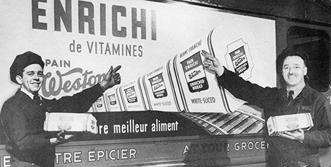 Dated Photo of 2 Men Infront of a Weston Advertisement